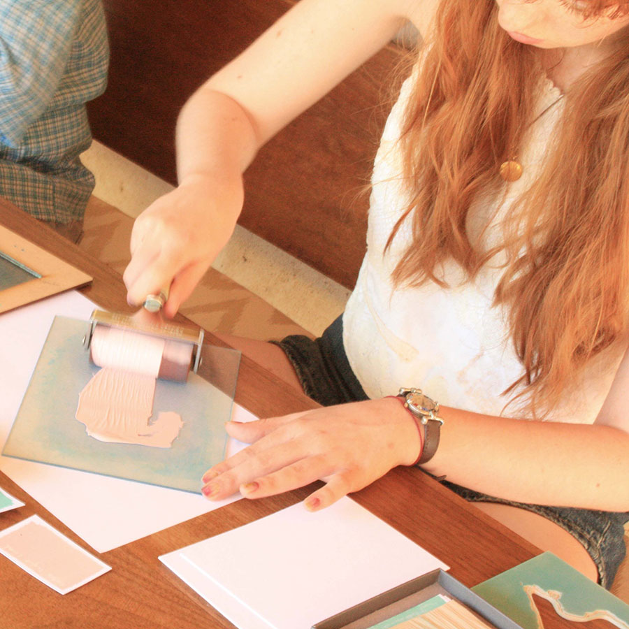 Smiling Hannah holding hand-printed summer sun postcards with yellow rays